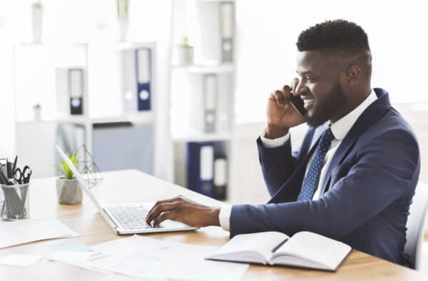 Cheerful young african entrepreneur having pleasant conversation with business credit union partner by phone